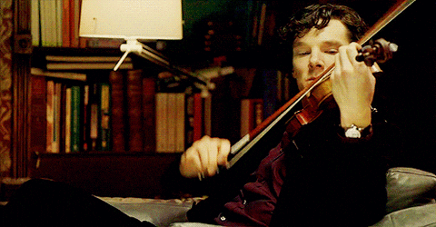 A man playing the violin in front of some books.